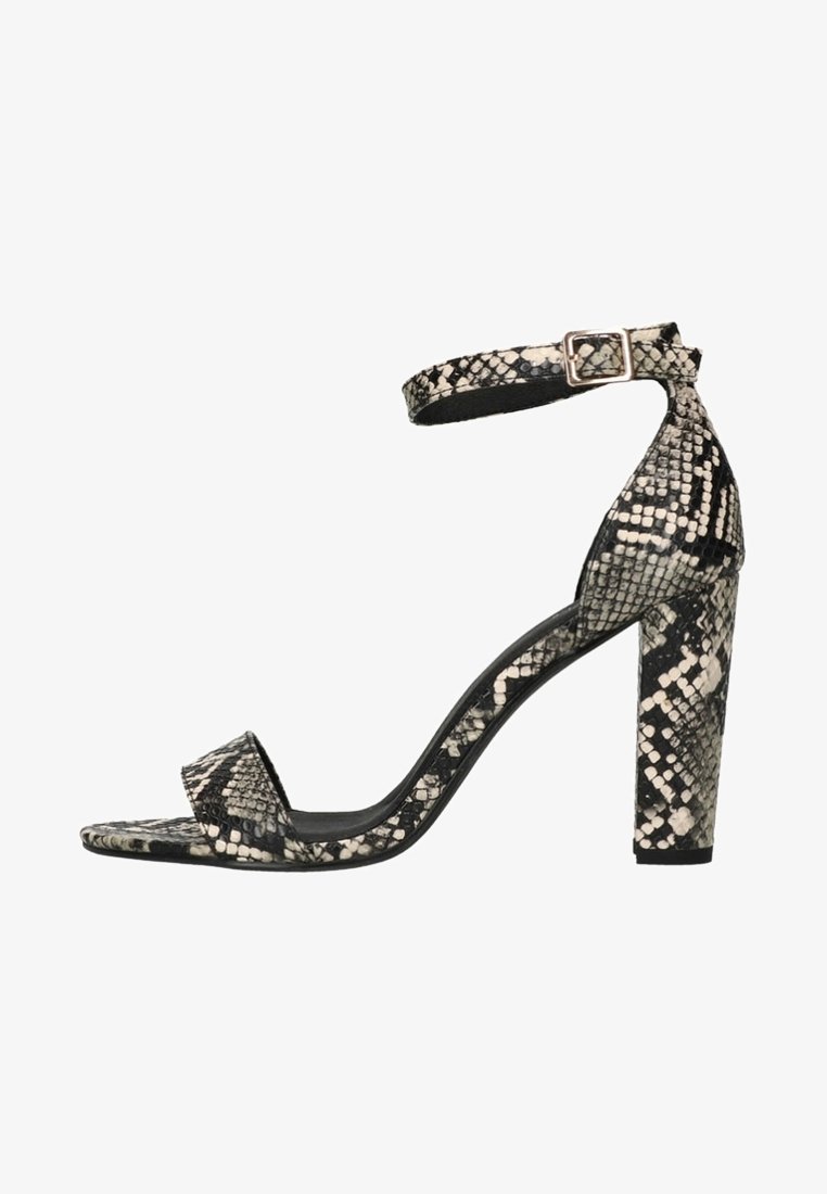Sandale à talon haut pour femme avec motif peau de serpent noir et blanc, équipée d'une bride de cheville avec une boucle carrée et un talon bloc.