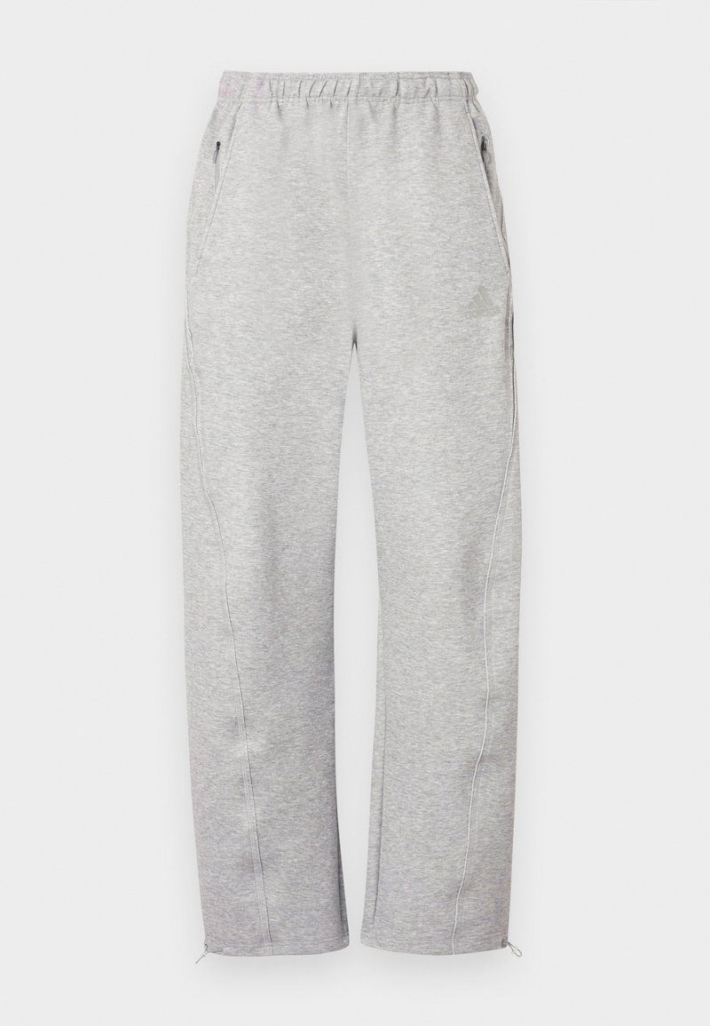 Pantalon de survêtement gris avec une ceinture élastique, des poches latérales et des ourlets zippés, fabriqué en textile doux avec une texture lisse. Détail de logo subtil.