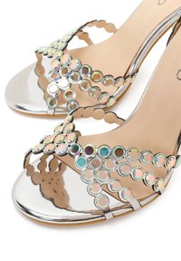 Zilveren open-toe hakken versierd met iriserende ronde edelstenen, gerangschikt in een kruiselings bandjesontwerp.