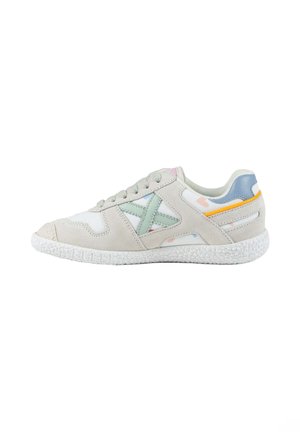 Deportiva casual beige claro con suela blanca texturizada, acento lateral verde claro, parche azul en el talón y pequeño detalle de raya naranja.