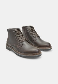 Stivaletti in pelle marrone con punta arrotondata, design con lacci, cuciture a contrasto e suola in gomma testurizzata.
