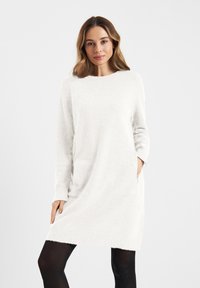 Jasnoszara, długosleeve sukienka swetrowa z miękkiego, teksturowanego materiału. Posiada okrągły dekolt i boczne kieszenie. Dół kończy się powyżej kolana.