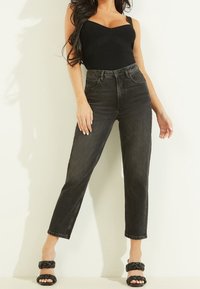Zwarte geribbelde bodysuit gecombineerd met hoge taille zwarte denim jeans. De jeans hebben een recht model en minimalistische details.