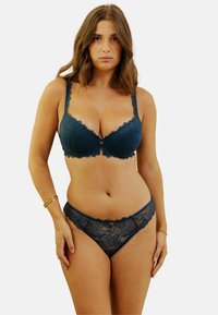 Soutien-gorge en dentelle bleu canard et culottes assorties avec motifs floraux, bords festonnés et détail doré au centre devant. Texture douce, design ajusté.