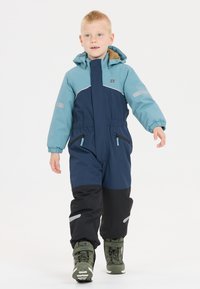 Blå och svart vinteroverall med dragkedja fram, elastiska manschetter och reflexdetaljer. Har två framfickor med dragkedja och en huva.