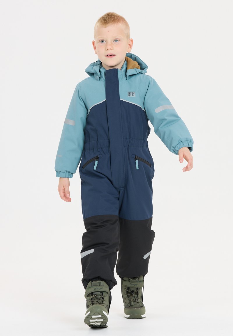 Blå och svart vinteroverall med dragkedja fram, elastiska manschetter och reflexdetaljer. Har två framfickor med dragkedja och en huva.