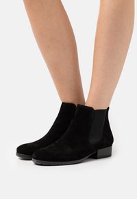 Stivaletti neri in suede con pannelli elastici ai lati, punta arrotondata e tacco basso a blocco. Superficie textured con dettagli lisci.