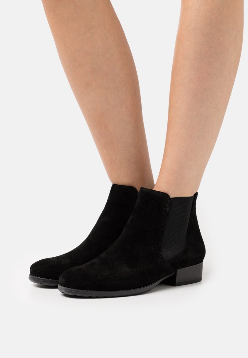 Stivaletti neri in suede con pannelli elastici ai lati, punta arrotondata e tacco basso a blocco. Superficie textured con dettagli lisci.