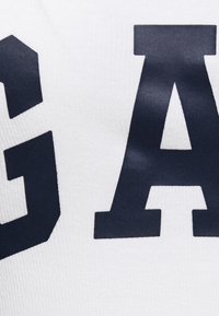 White fabric with dark blue block letters "G" and "A," featuring a smooth texture and a close-up view of the print design.