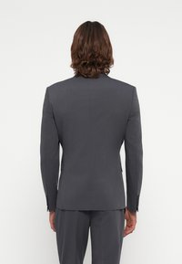 Gray suit jacket with a tailored fit. Notable features include structured shoulders, a smooth texture, and a single vent at the back.