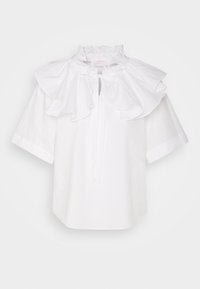 Blouse blanche à manches courtes avec un col volanté, une fermeture par un ruban noué au cou, et une silhouette carrée. Texture en coton lisse.