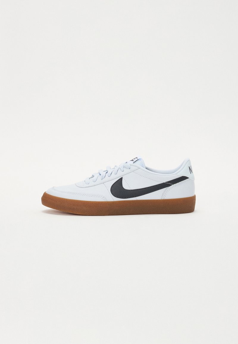 Světlé modré tenisky s černým logem Nike. Mají strukturovanou gumovou podrážku a hladký svršek, bílé šněrování a branding na patě.