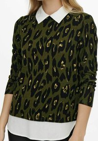 Maglione verde con stampa leopardata nera e dorata, scollo a giro, maniche lunghe e dettagli di orlo bianco a strati.