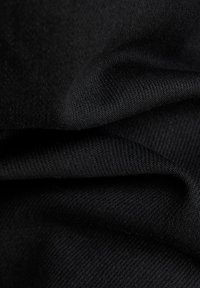 Țesătură neagră cu o textură netedă, prezentând un tricot fin și o ușoară strălucire, afișând pliuri și drapaje stratificate.
