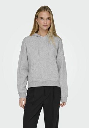 Grey hoodie with a relaxed fit, drawstring hood, front pocket, soft texture, and ribbed hem, paired with black tailored trousers.