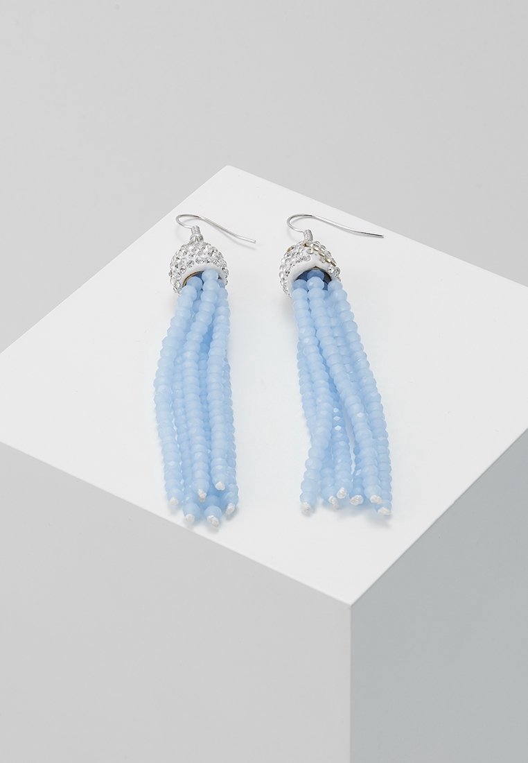Boucles d'oreilles à crochet en argent avec plusieurs rangs de perles bleu clair suspendues en style pampille sur une surface blanche inclinée.