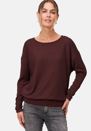 Pull en tricot bourgogne à coupe ample, avec un large col et des manches longues. Tissu texturé, poignets et taille côtelés. Assorti avec un jean gris.