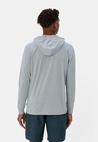 Felpa a maniche lunghe grigia chiara con una vestibilità rilassata e cappuccio regolabile. Abbina a pantaloni corti grigi scuri, che mostrano un tessuto morbido e un design informale.