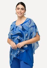 Top trasparente blu e azzurro chiaro con motivi astratti, caratterizzato da un colletto a girocollo e tessuto fluente che si adagia su una base blu solida.