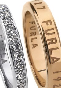 Două inele: unul este un band de argint cu pietre clare fasetate, iar celălalt este un band de aur, gravat cu "FURLA" și cu un finisaj neted.