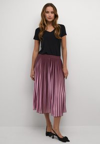 Schwarzes V-Ausschnitt-Top kombiniert mit einem plissierten Midi-Rock in den Farben Weinrot und Pink, mit einem glatten Bund und fließendem Design.