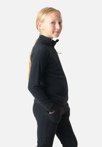 Czarna polarowa kurtka z wysokim kołnierzem i zamkiem, zestawiona z dopasowanymi czarnymi spodniami. Gładka tekstura, zaprojektowana dla komfortu i ciepła.