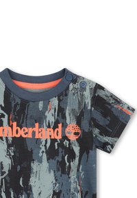 Katoenen T-shirt met een blauw en grijs abstract patroon, korte mouwen en een oranje Timberland-logo met twee knopenaccenten nabij de kraag.