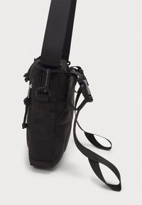 Borsa a tracolla nera in nylon con texture trapuntata, cinturini regolabili, numerose tasche e chiusure per una sicurezza ottimale.