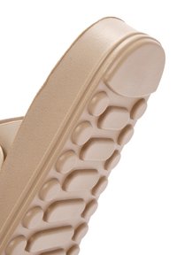 Beige rubber sandal with a textured sole featuring round raised dots for grip and a smooth upper edge.