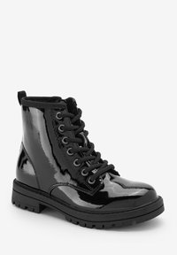 Bottines à lacets en cuir verni noir brillant avec semelle en caoutchouc, bout rond et col rembourré pour le confort ; œillets en métal pour les lacets.