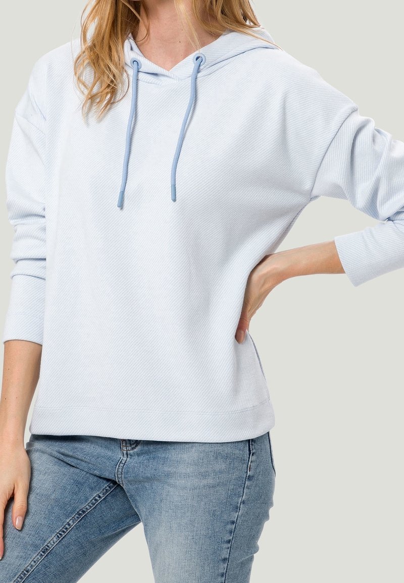 Hoodie bleu clair à côtes avec une poche kangourou, capuche à cordon et manches longues, associé à un jean en denim bleu.