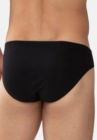 Schwarzer Baumwollstring mit glatter Textur, elastischem Bund und einer figurschmeichelnden Passform, die von hinten einen schlichten, minimalistischen Stil zeigt.