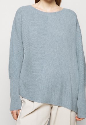 Pull en maille côtelée bleu clair avec une coupe décontractée, col rond large et fentes sur les côtés. Présente des textures variées à l'avant et à l'arrière.
