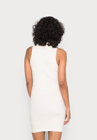 Vestido branco justo de alças com um design ajustado e corte sem mangas, apresentando um decote alto e um comprimento até meio da coxa. Rótulo minimalista nas costas.