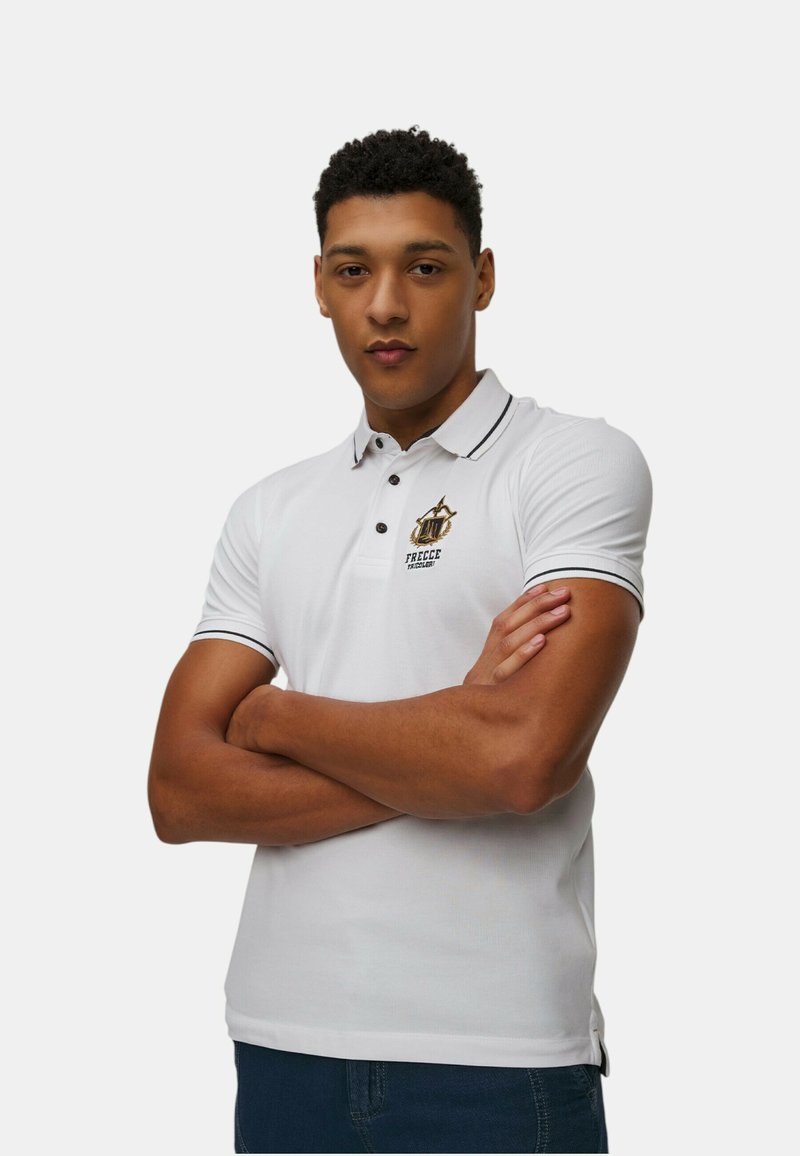 Polo shirt bianco con dettagli neri e un logo sul petto. Maniche corte, design con colletto e forma aderente. Texture morbida.
