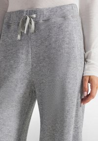 Grijze gebreide joggers met een trekkoord in de taille, met een zachte textuur en zijzakken; zichtbare stiksels langs de naden.
