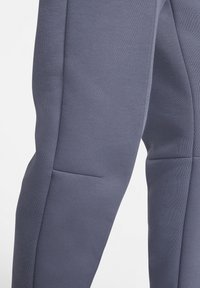 Grijze sportieve joggingsbroeken die goed aansluiten, met een textuurstof, zijnaad en een subtiel zakdetail op de linkerdij.