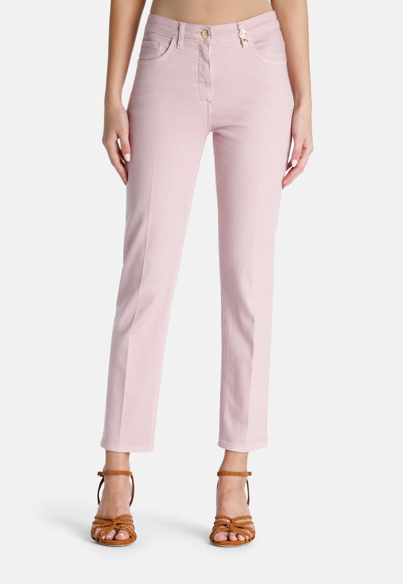 Jeans rectos de color rosa claro con bolsillos frontales, cierre de botón y detalles de costura sutiles. Combinados con sandalias tiras en color marrón.