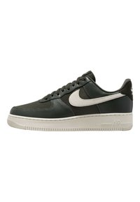 Nike Air Force 1 sneakers i mörkgrönt läder med en krämfärgad mellansula, med en framträdande vit swoosh och texturerade detaljer.