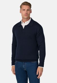 Jūras spēku stila džemperis ar ribotu tekstūru, ar plašu apkakli un pusi pogu aizdares. Apakšā valkāts balts krekliņš ar apkakli.