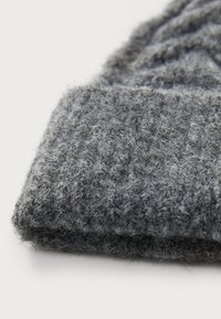 Sivi pleteni šešir s teksturiranim, dlačicastim materijalom. Materijal izgleda mekano s rebrastim uzorkom za dodatnu toplinu i udobnost.