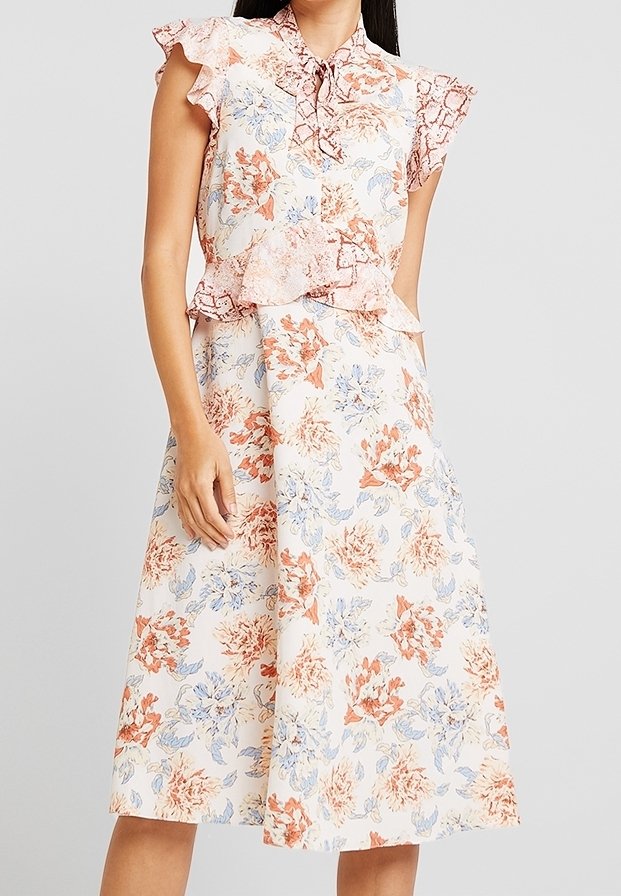Blommig midiklänning i ljus krämfärg med rosa och blå blommönster. Har volangärmar och en figurnära bodice med peplumdetalj.