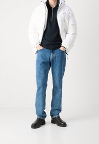 Vit pufferjacka, svart dragkedjetröja, blå denimjeans och svarta läderstövlar. Enkelt mönster, mjuk textur och mångsidiga färger.