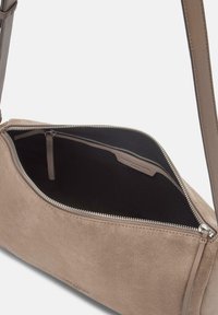 Borsa a tracolla in suede beige con chiusura a zip, dotata di una tracolla in pelle liscia e un ampio interno foderato in tessuto nero.