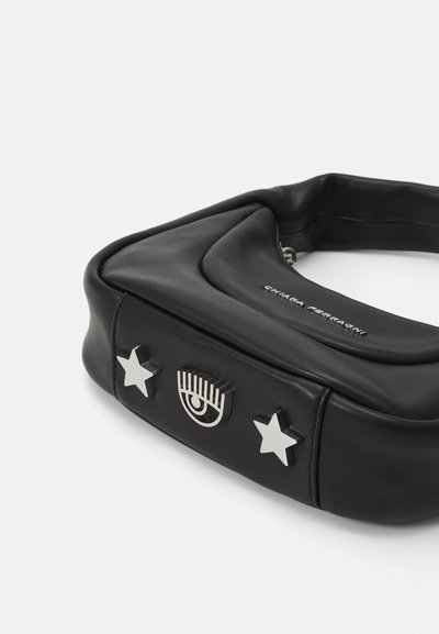 Melna mākslīgā āda soma ar kvadrātveida formu, kas ir izstrādāta ar sudraba detaļām, tostarp zvaigznēm un acs dizainu. Gluda tekstūra un minimālisma stils.