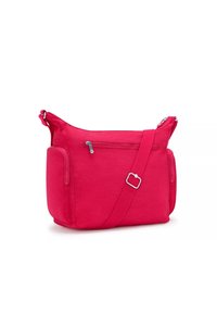 Röd tyg crossbody-väska med silverdetaljer, blixtlåsförsedd framficka och avtagbar axelrem. Slät yta, praktisk design.