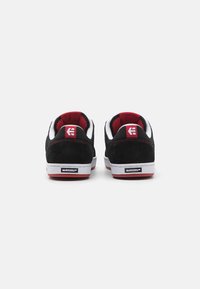 Black suede skate shoes with white accents and a red lining, featuring a padded tongue and ankle collar, rubber outsole with Michelin branding.