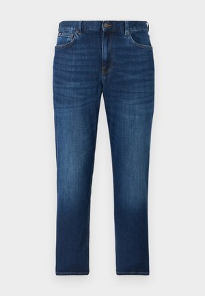 Mørkeblå denimjeans med let falmet effekt, forlommer, bæltestropper og knaplukning på en ensfarvet baggrund.
