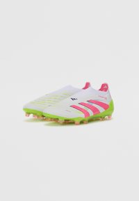 White soccer cleats with pink accents and green outsole, featuring textured surface patterns and a sleek, streamlined design.