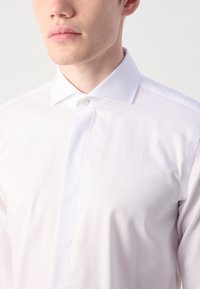 Witte dress-shirt met een standaard kraag, enkele knoopsluiting en een gestructureerd patroon, vervaardigd uit een gladde stof.